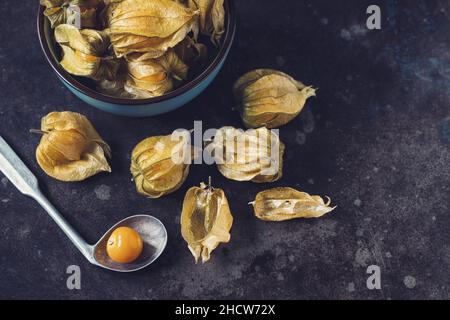Physalis fruits (Physalis Peruviana) with in a ceramic bowl and spoon on dark background Stock Photo