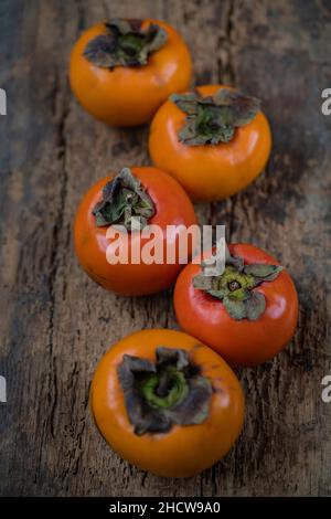 persimmon fruit, top view of asian or blacksea persimmon fruits on wooden background with selective focus and noise effects Stock Photo
