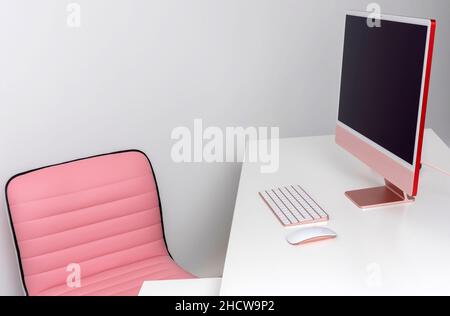 England, UK. 2021. A white office desk and a pink chair, desktop computer and keyboard with mouse. Stock Photo