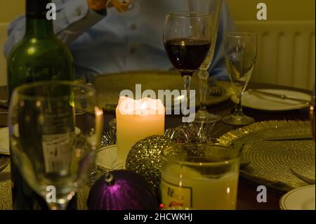 Candle lit table before or after a Christmas dinner with defocused wine glasses & plates in the dining room Stock Photo