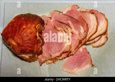 Selective focus close up on smoked gammon meat on a wooden board. The meat is sliced for eating Stock Photo