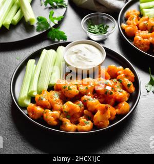 Cauliflower buffalo wings on black stone background. Close up view Stock Photo