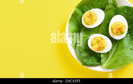 Close up view of deviled eggs with paprika, mustard and mayonnaise on yellow background with free text space. Top view, flat lay Stock Photo