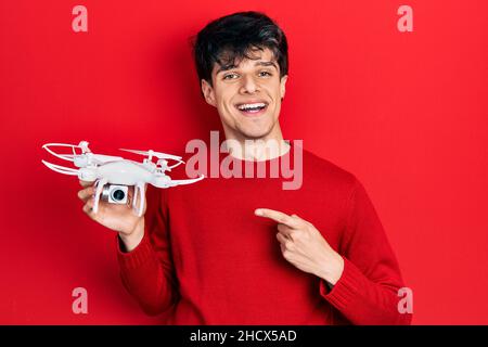 Handsome hipster young man holding drone smiling happy pointing with hand and finger Stock Photo