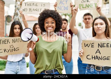 Group of young friends protesting and giving slogans at the street surprised with an idea or question pointing finger with happy face, number one Stock Photo