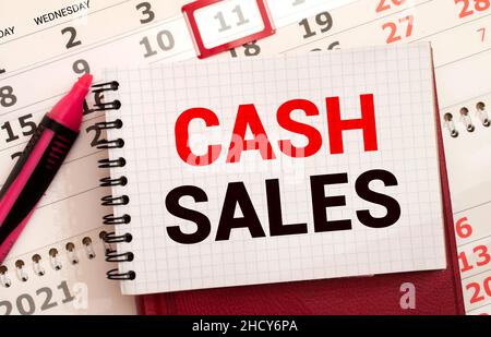 On the table there is a red marker and a white paper tablet on which the text is written - CASH sales, red and black letters. Business concept. Stock Photo