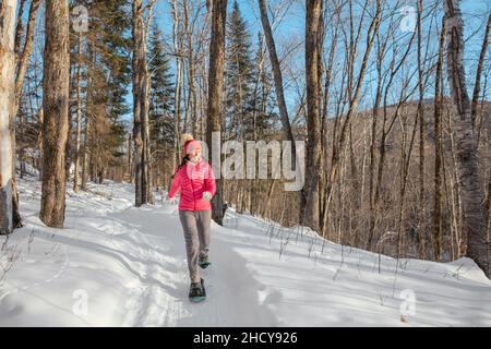 Winter snowshoe woman hiking. Snowshoeing asian biracial woman in winter forest on hike in snow wearing snowshoes living healthy active outdoor Stock Photo