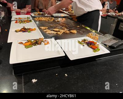 Diners waiting for chef in Japanese food teppanyaki restaurant. Dishes from vegetables,beef,fish, shrimp and chicken are being prepared in real-time. Stock Photo