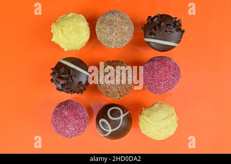 Chocolate pralines top view stock images. Chocolate candies on an orange background. Chocolate frame top view. Square-shaped  chocolate pralines backg Stock Photo