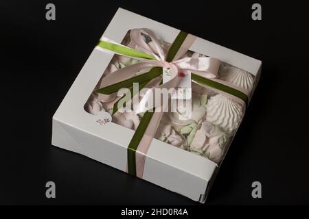 Homemade marshmallow in a gift box. Tied with a ribbon tied to a bow. On a black background. Close-up. Stock Photo