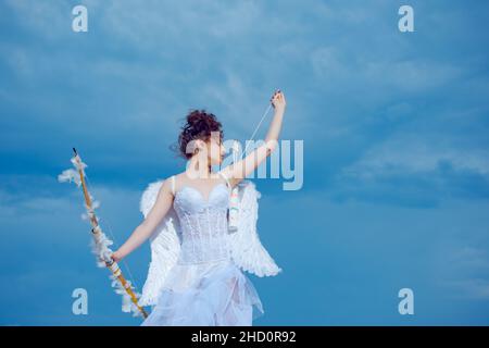 Cupid girl, cute teen on valentine day with bow arrow shooting. Valentin teenager angel with wings. Arrows of love. Stock Photo