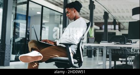 businessman working on a new software programme. Focused young software developer using a laptop while working in an office. Creative businessman sitt Stock Photo