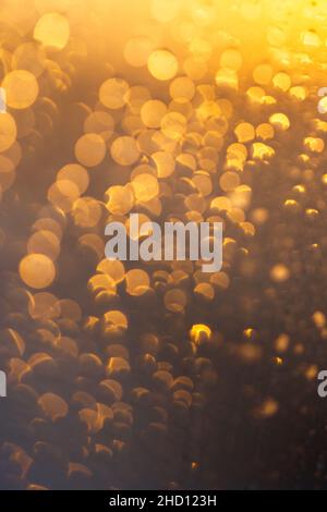 Abstract circular gold and orange bokeh sunlight reflection glass of window. Rain drops texture. Stock Photo