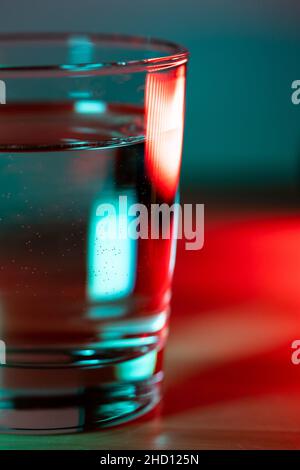 Macro shot of glass of water in red blue trendy neon light.  Stock Photo