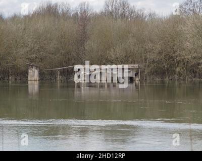 A small old wooden house close to the bank of a river is affected by a huge flood. Stock Photo