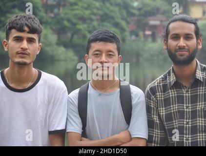 Closeup of three male friends looking at camera, posing for photo beside the lake Stock Photo