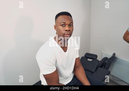 Serene young man seated in physiotherapist office Stock Photo