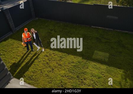 Female construction engineer with worker smiling and pointing at camera Stock Photo