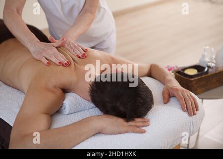Unrecognizable man relaxing at spa center, getting professional back massage Stock Photo