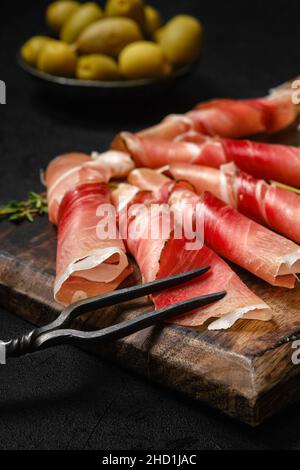Rolled slices of jamon on wooden serving board Stock Photo