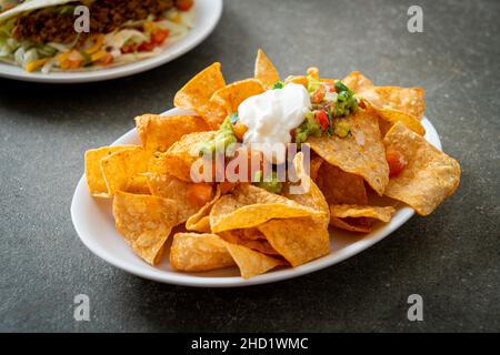 Mexican nachos tortilla chips with jalapeno, guacamole, tomatoes salsa and dip Stock Photo