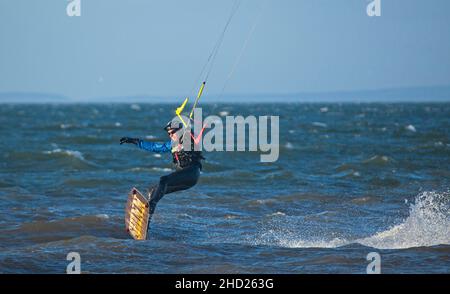 Longniddry, East Lothian, Scotland, UK. 2nd January 2022. Gusty wind at 20 km/h with potential gusts of 35 km/h temperature of 8 degrees for the few kitesurfers who ventured out on the choppy Firth of Forth. Conditions gave good potential for the experienced surfers to get some good air. Credit: Arch White Stock Photo