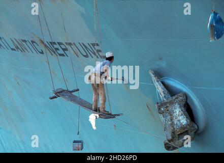 Seaman standing on a plank and painting ship, 'Atlantic Neptune', very unsafe, possibly in the Persian Gulf. Sometime between May and September 1977 Stock Photo