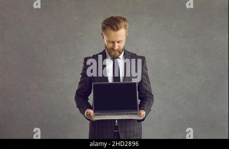 Studio shot businessman shows laptop black screen blank screen monitor for text Stock Photo