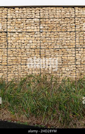 Close up of a stone Gabion basket wall and grass. England, UK Stock Photo