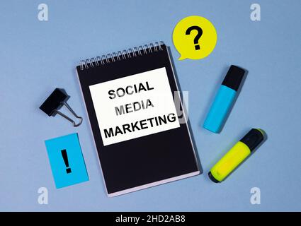SMM Social Media Marketing written on notepad with markers clips and memo nte around on blue table. Yellow Blue and Black SMM concept Stock Photo