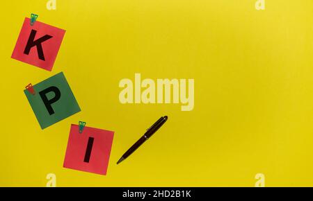 KPI word on green and red stickers with clips and pen on yellow background with copy space Stock Photo