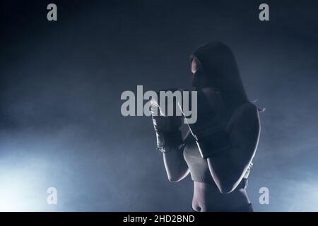 Side view of a silhouette young woman with boxing gloves making a direct hit. Stock Photo