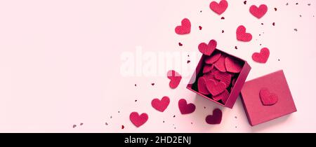 Open gift box and knitted hearts on pink background, top view. Valentines day greeting card. Flat lay style. Stock Photo