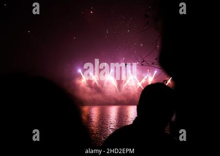 Bucharest, Romania - January 1, 2022: People watch fireworks during New Years celebrations in the Alexandru Ioan Cuza park in Bucharest. Stock Photo