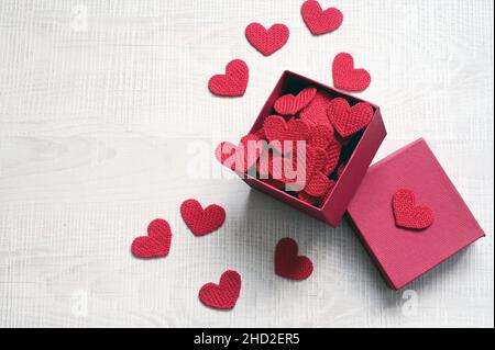 Open gift box and knitted hearts on light background, top view. Valentines day greeting card. Flat lay style. Stock Photo