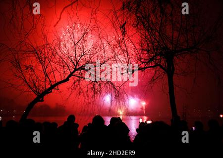 Bucharest, Romania - January 1, 2022: People watch fireworks during New Years celebrations in the Alexandru Ioan Cuza park in Bucharest. Stock Photo