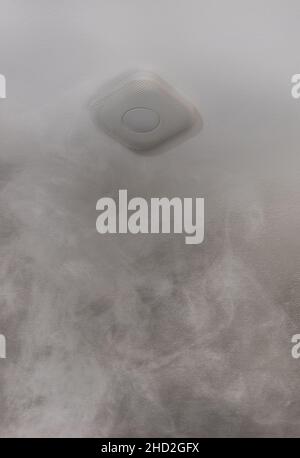 smoke detector on the ceiling of a room full of smoke Stock Photo