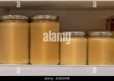 Set of glass bottles with honey, jam, marmalade, jams, preserves, syrups, on a shelf Stock Photo