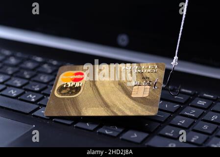 Internet fraud using computer technology, stealing money on the Internet, stealing credit card data. Hook hooked credit card on laptop keyboard backgr Stock Photo