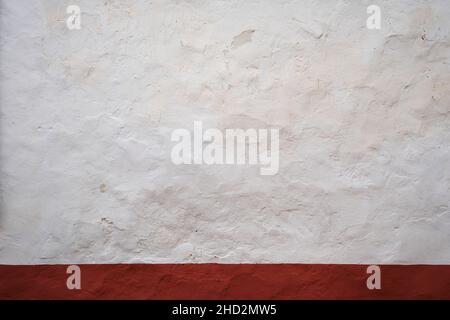 Old whitewashed lime wall with red skirting board, traditional architecture in La Mancha, Spain Stock Photo