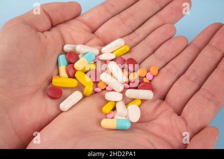 Man holding assorted multicolored medicine pills, capsules and tablets in his hands. A handful of pills. Immune system vitamins and supplemets. Dietar Stock Photo