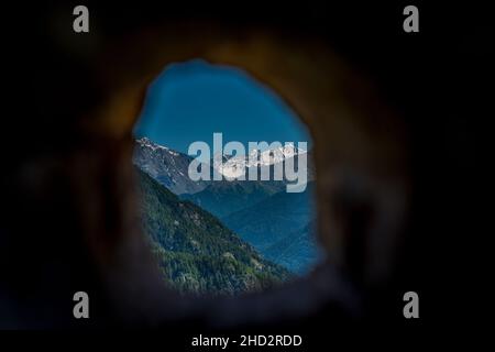 mountain panorama with snowy white mountain in the background. Photo taken in the middle of a tree trunk Stock Photo