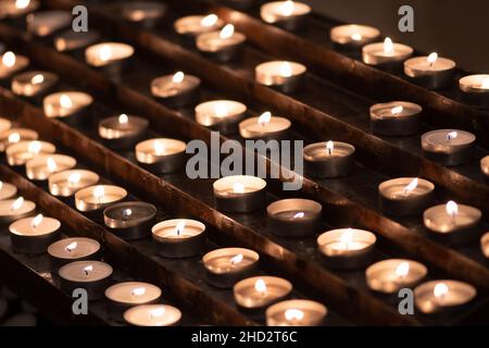 Many candles in a row glowing with a golden yellow light Stock Photo