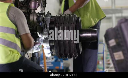 Calm workers controlling aircraft machine. Aircraft maintenance mechanic inspects plane chassis. Engine and chassis of the passenger airplane under he Stock Photo