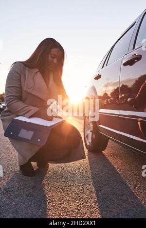 insurance agent examines the car. Accident claim process. African-American woman checking the damage to the car after an accident. Transportation conc Stock Photo