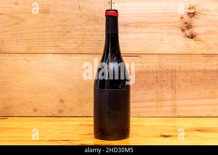 Bottle of red wine without signs in gold color and wooden background Stock Photo