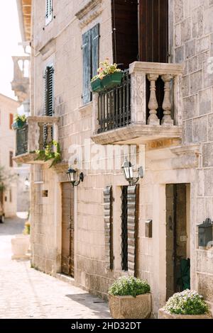 Stone balconies with flowerpots on the stone facade of the house Stock Photo