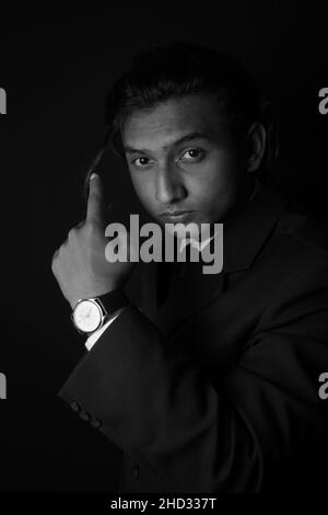 Vertical grayscale shot of an Indian man wearing a classy suit and watch Stock Photo