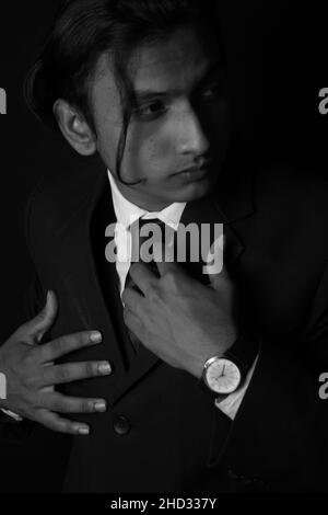 Vertical grayscale shot of an Indian man wearing a classy suit and watch Stock Photo