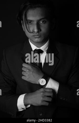 Vertical grayscale shot of an Indian man wearing a classy suit and watch Stock Photo